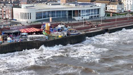 Slow-motion-waves-breaking-on-seafront-funfair-Bridlington-UK-drone,aerial