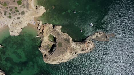 Vista-De-Pájaro-De-Arriba-Hacia-Abajo-De-Los-épicos-Acantilados-Oceánicos-Rodeados-De-Ondas-Verdes-Reflectantes,-Antena-De-Drones