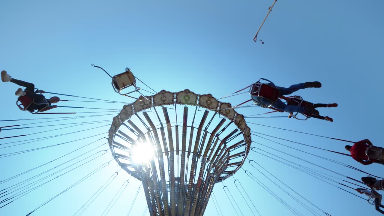 실루 사람들은 놀이 공원에서 움직이는 스 체인 카루셀을 타고 있습니다.