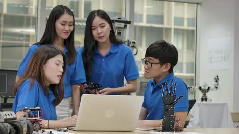 young asian creative engineers meeting, programming for collaborative universal robotics at laptop in workshop. people with technology or innovation concept.