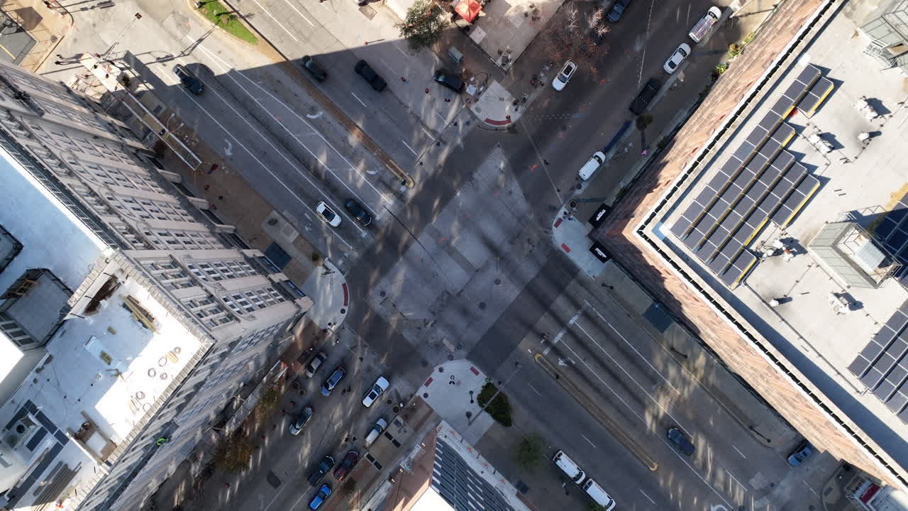 Birds eye drone footage of downtown city streets at sunrise showing steady morning traffic flow and organized urban movement