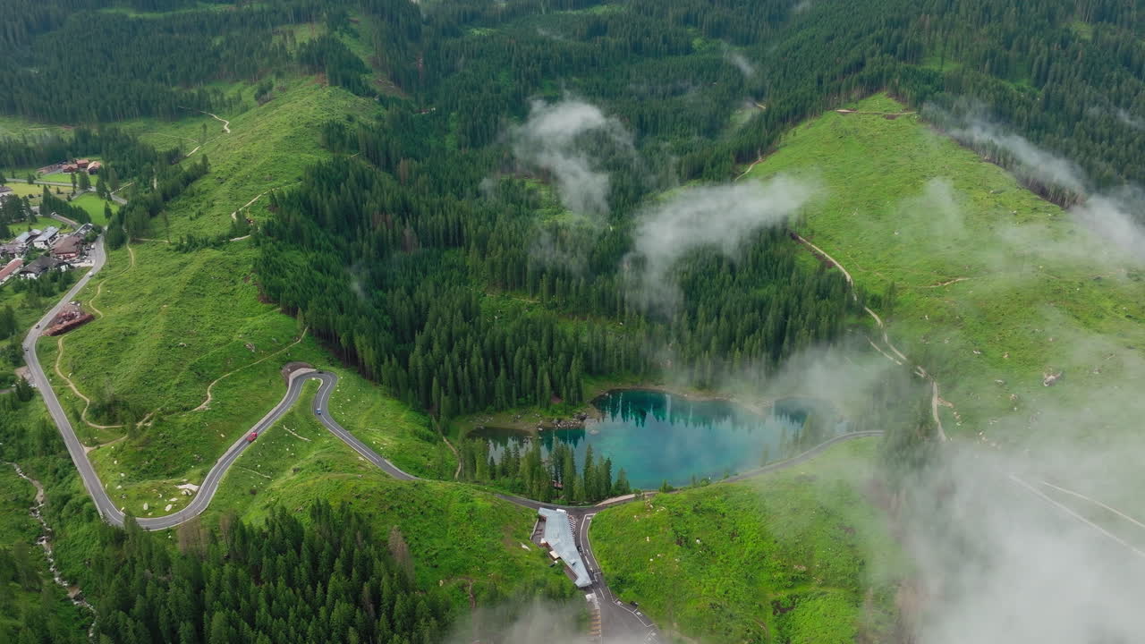 Drone panorama of Lago di Carezza in South Tyrol, Italy. A vibrant spring landscape with evergreen trees and turquoise waters