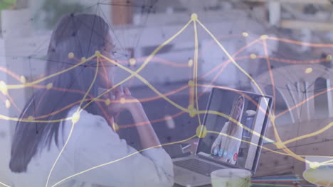 woman sitting at desk, joining technology meeting on laptop, with network data lines floating