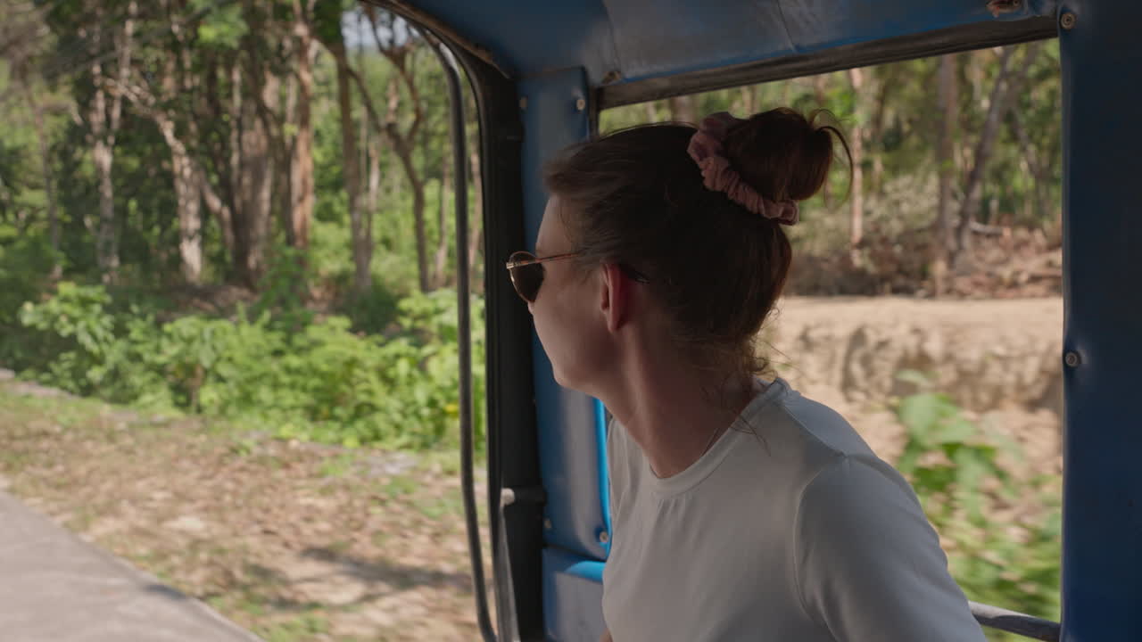 Donna che viaggia attraverso la natura mozzafiato della Thailandia mentre si gode un giro in tuk-tuk assistendo al