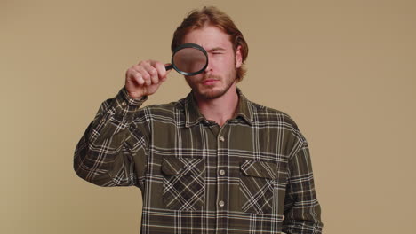 investigator researcher man with magnifying glass near face, looking into camera with big zoom eye