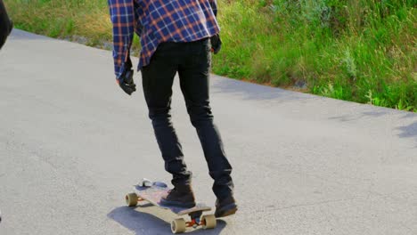 Rear-view-of-young-caucasian-skateboarders-skating-on-downhill-at-countryside-4k