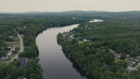 calm waters of river flowing through green forests in sherbrooke, canada - drone shot