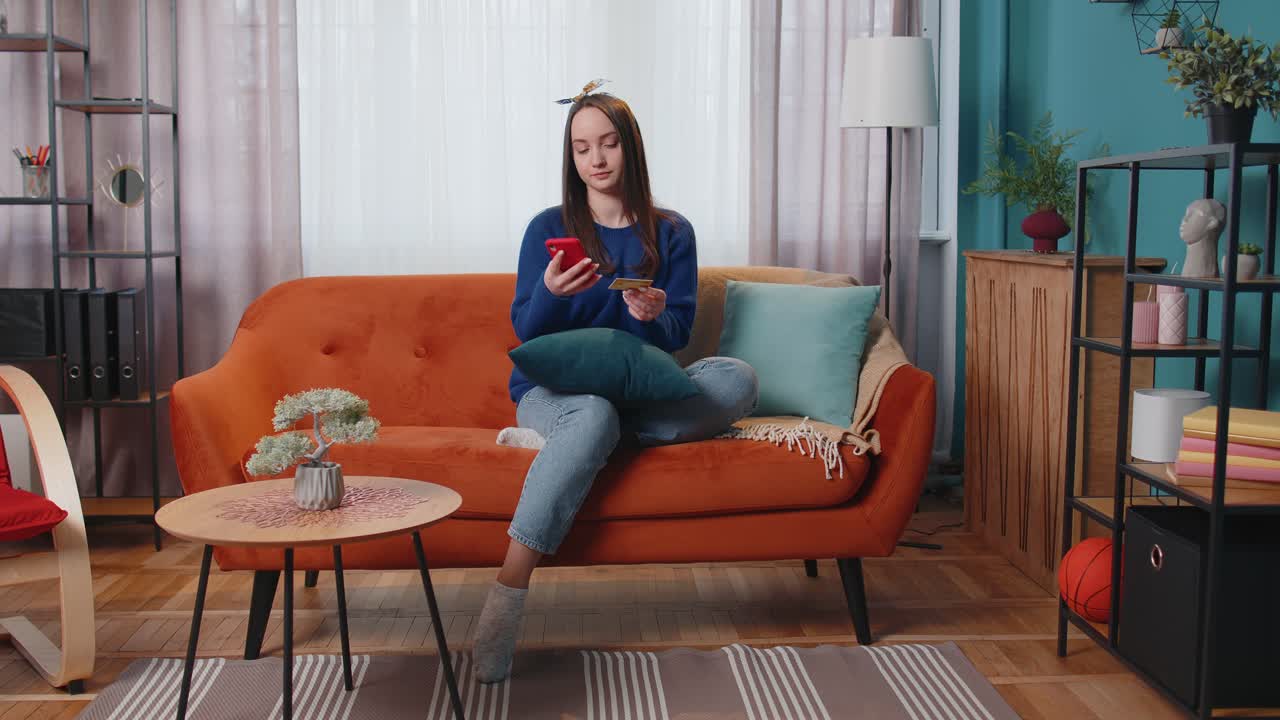 온라인 쇼핑을 통해 돈을 송금하는 동안 신용 은행 카드와 스마트폰을 사용하여 집에 앉아있는 여성