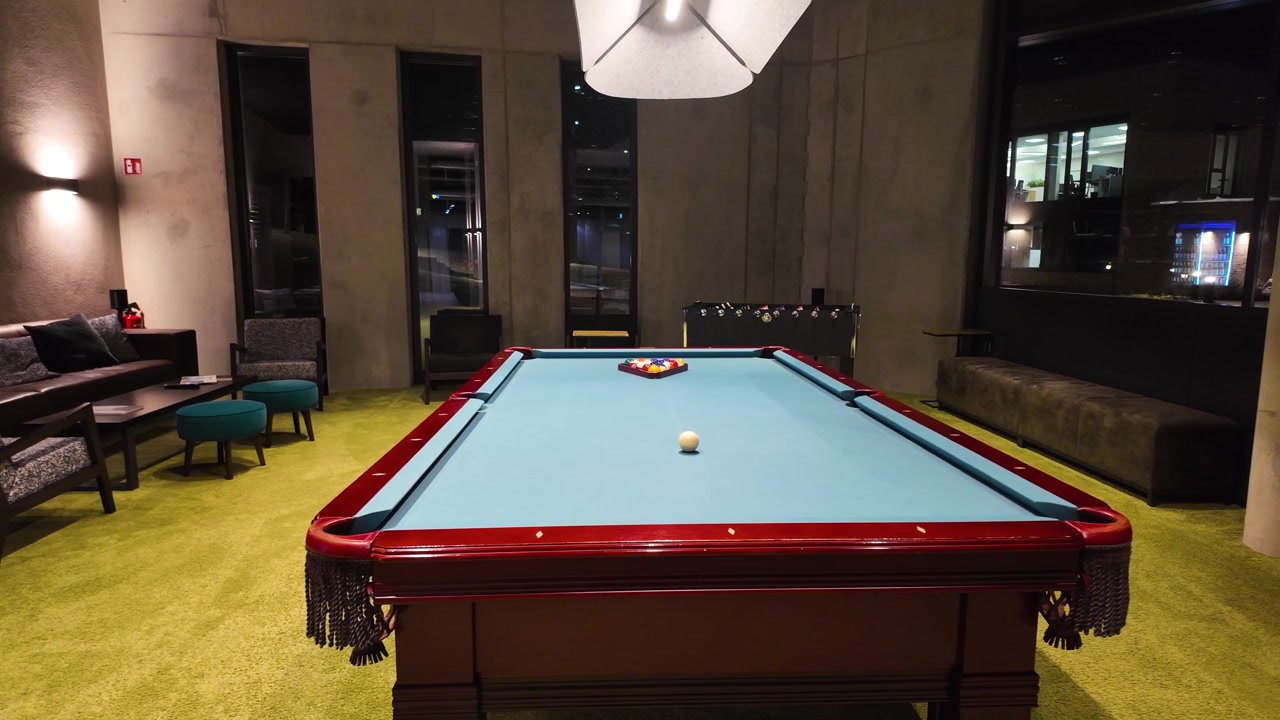 A pool table in a cozy room with sofas and armchairs
