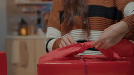 Close-up-of-woman-wrapping-bow-on-gift-for-friends