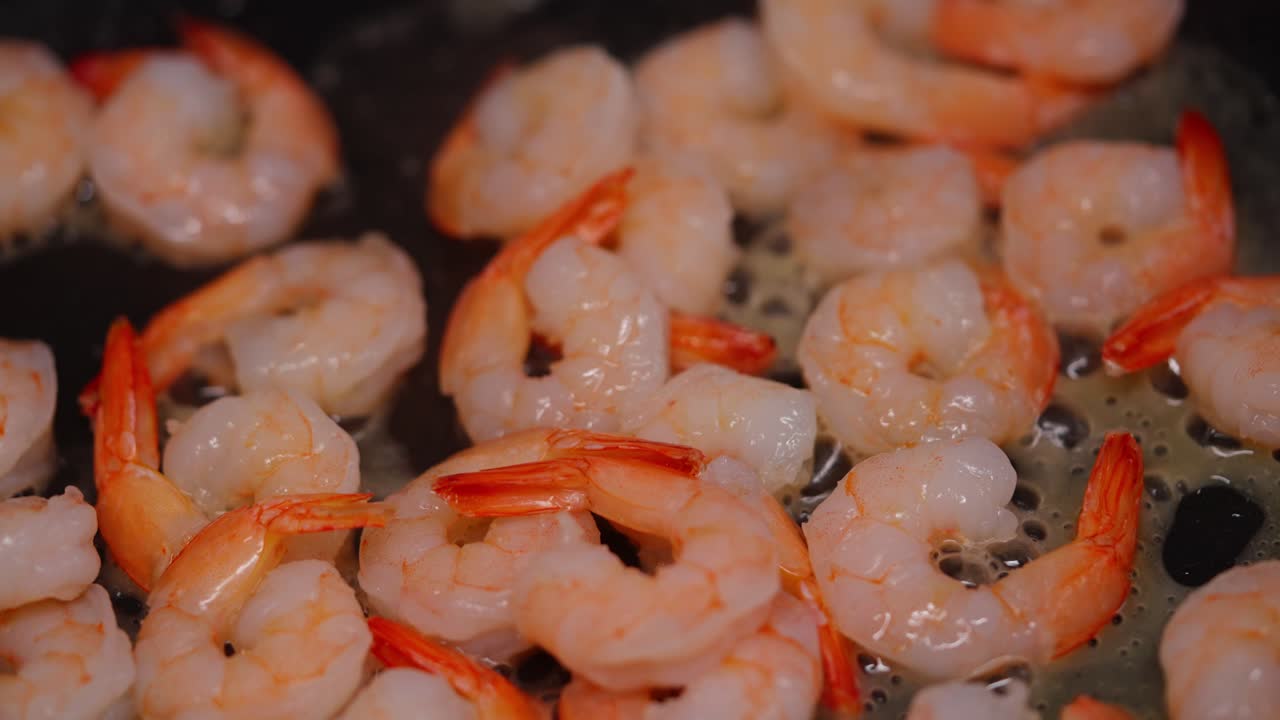 Fresh shrimp sauteing in hot pan with steam and golden crust forming during frying saute process with steam