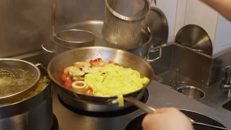 Preparación-De-Tagliatelle-De-Espaguetis-Mediterráneos-De-Mariscos-Italianos-En-Una-Cocina-Tradicional-De-Restaurante,-Pasta-Mezclada-En-Una-Sartén-Con-Sopa-De-Salsa-De-Pescado