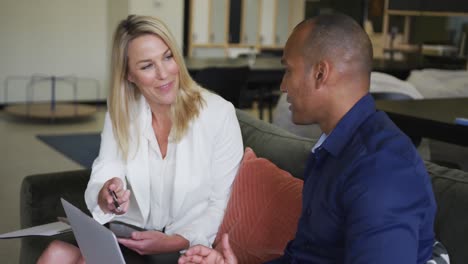 two diverse business colleagues using laptop laughing and discussing in a casual meeting