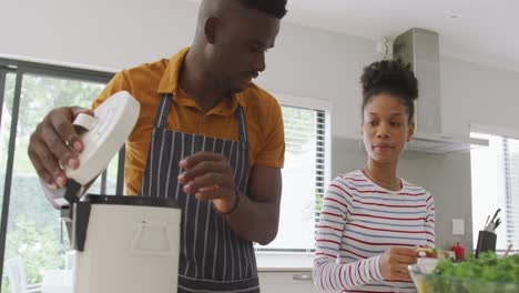 Video-of-happy-african-american-couple-cooking-together-in-kitchen