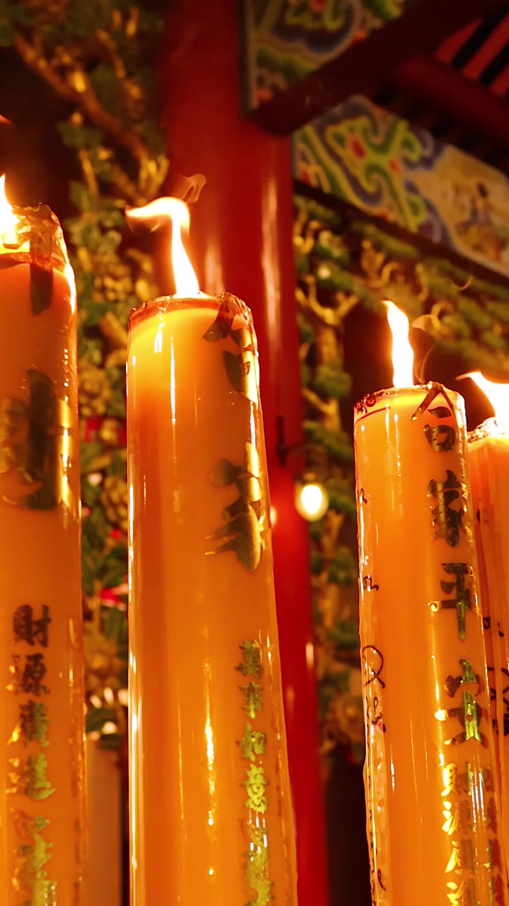 Grandi candele gialle tremolano in un tempio ornato, illuminazione calda, leggero movimento della telecamera, atmosfera notturna