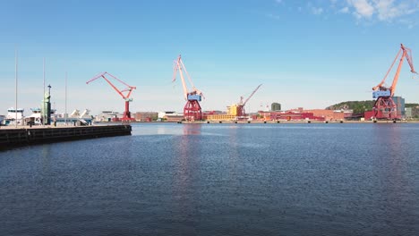 Drohne,-Die-Tagsüber-über-Dem-Wasser-Fliegt,-Mit-Blick-Auf-Hafenkräne-Im-Industriehafen-Von-Göteborg-In-Schweden---Niedrige-Antenne