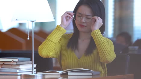 portrait of happy joyful pretty female student busy hard working sitting against background of bookshelves in university library holding laptop and backpack looking to the side, smiling pleasant