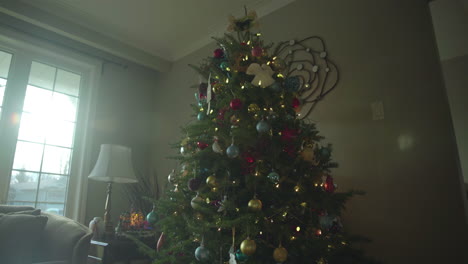 muñeco de árbol de navidad con adornos y sol entrando por la ventana creando un hermoso destello de lente