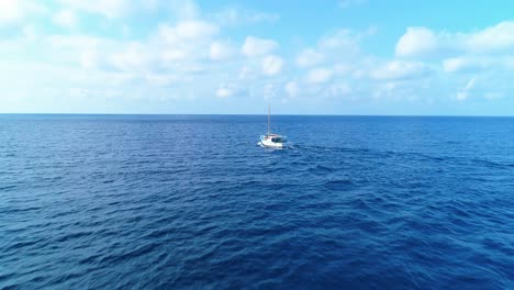 El-Dron-Vuela-Hacia-El-Mástil-Del-Velero-Y-Una-Pequeña-Estela-Que-Conduce-Hacia-El-Mar,-Horizonte-Nublado