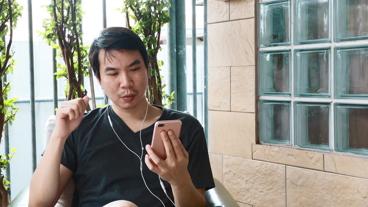 음악을 듣기 위해 스마트폰을 사용하는 아시아인