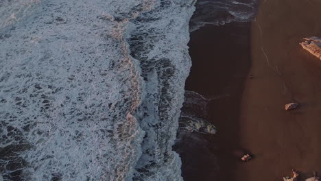 Luftbild-Von-Oben-Auf-Die-Wellen-Am-Strand-Von-Nazare-In-Portugal-Während-Des-Sonnenuntergangs