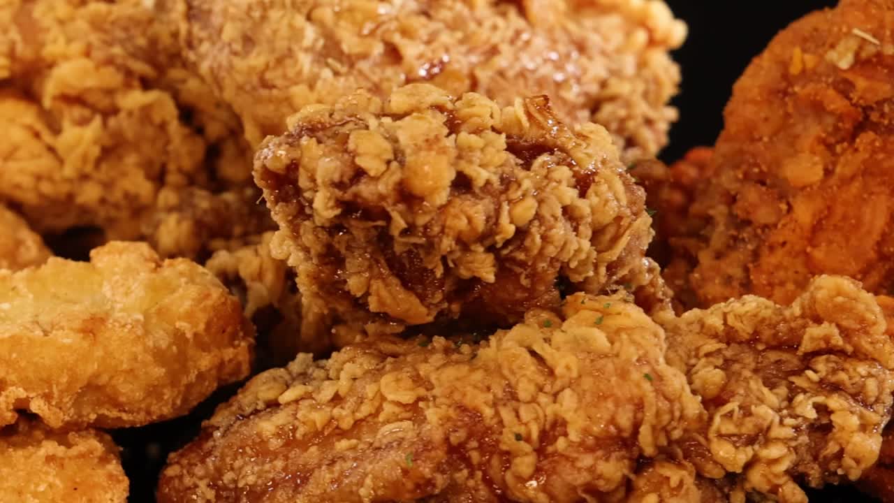 어두운 배경에서 회전하는 다양한 빵가루 입힌 닭날개와 너겟을 극단적으로 클로즈업한 이미지