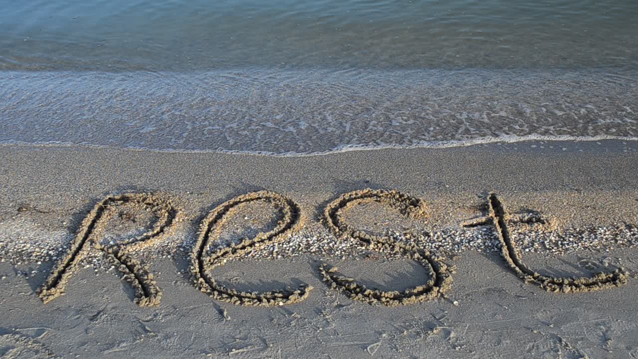 Inscription rest on sand, the beach. Inscription on sand, the beach