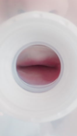 thirsty child holds transparent plastic bottle and sucks silicone nipple. little boy lips move trying to drink water or milk. view from bottom macro