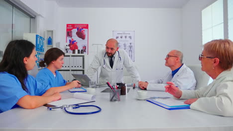 Doctor-discussing-with-medical-staff-in-hospital-conference-room