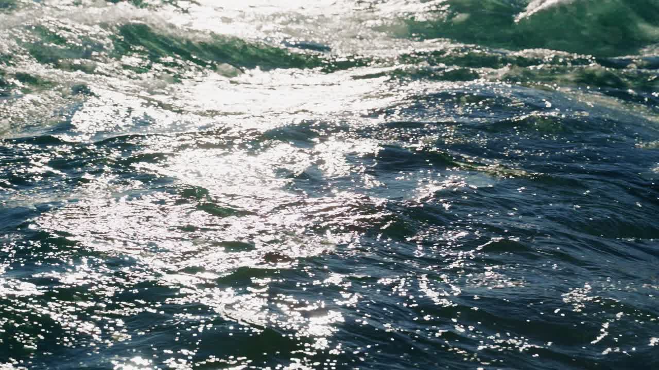 Onde che si infrangono dolcemente e luccicano riflettendo la luce del sole su una costa tranquilla. La scena cattura la quiete della natura a mezzogiorno, mostrando la bellezza dell'oceano.