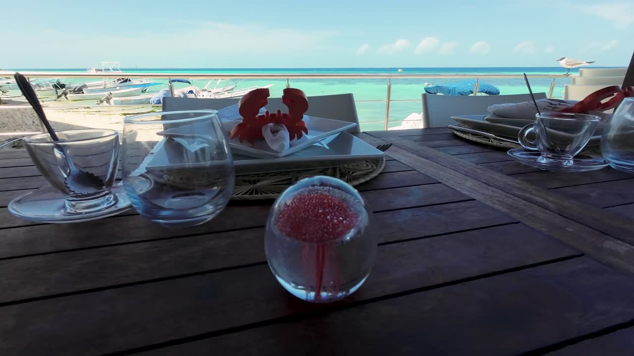 A Caribbean beach house, guests enjoy cocktails surrounded by ocean-themed decor and beautiful sea views. A relaxed atmosphere for unwinding with a cool drink and soaking in the peaceful setting.