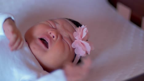 a newborn baby lying in a crib and crying, when her mother picks her up