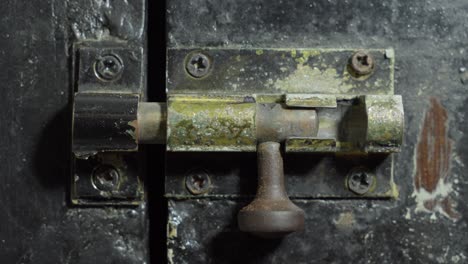 hand locking sliding old rusty door latch lock, close up