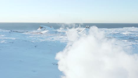 winter landscape in iceland with reykjanes lighthouse and steam from geyser