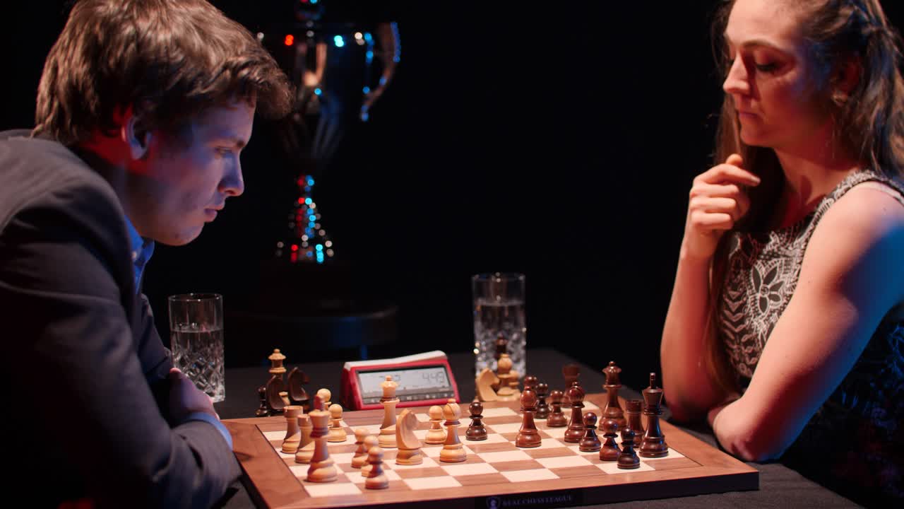 Male and female opponent compete in intense timed chess tournament match with silver trophy in the background