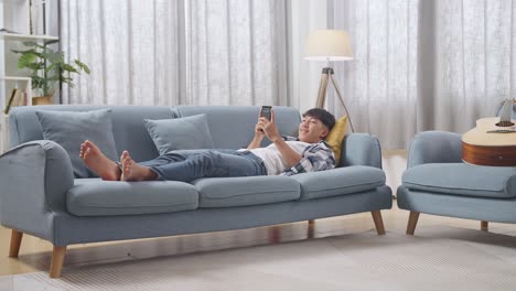 teenager relaxing on couch with smartphone