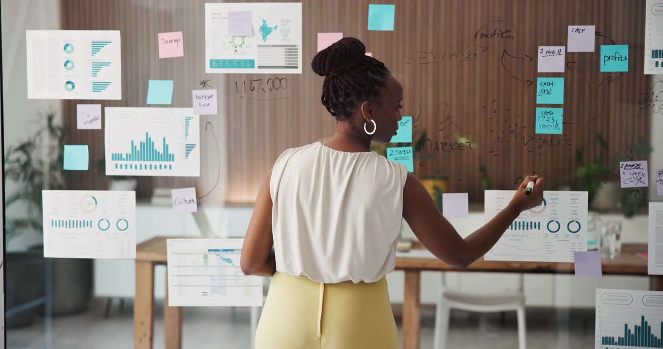 Professional Woman Writing on Glass Wall in Modern Office
