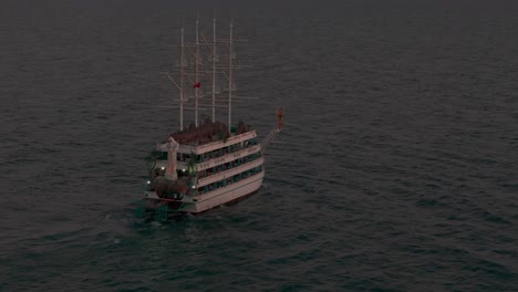 aerial view observing multi level tourist sailing ship floating across idyllic mediterranean sea at sunset