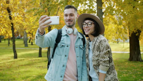 una pareja tomando una selfie en un parque de otoño