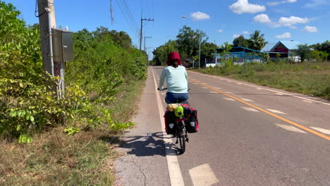 Una-Filmación-Dinámica-De-Una-Mujer-Que-Viaja-En-Bicicleta-Con-Alforjas-Y-Comestibles-En-La-Parte-Trasera