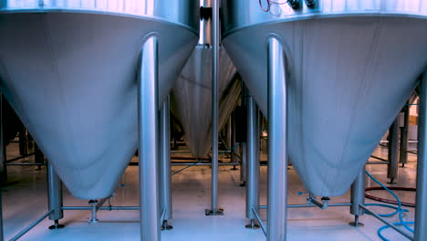 Rack focus from large stainless steel beer fermentation tanks in a brewery to blurry out-of-focus view