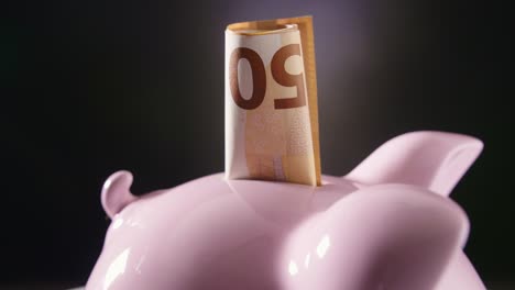 closeup of piggybank with currency turning on table