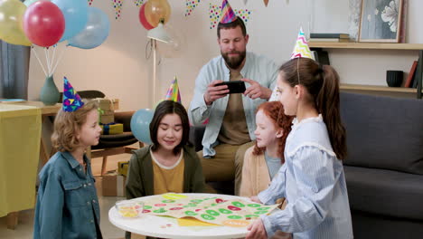 niños con sombreros de fiesta jugando a un juego de mesa