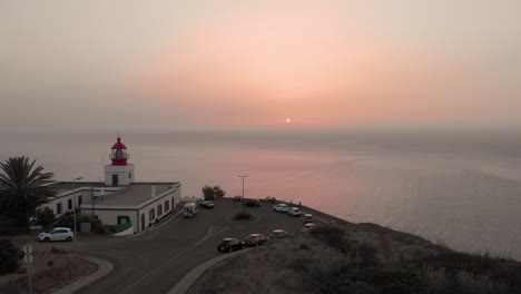 increíble faro con vistas al paisaje del mar aéreo de drones al atardecer con nubes rosas, en españa