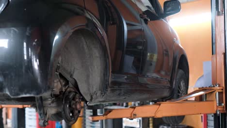 black car on a hydraulic lift in a garage for maintenance