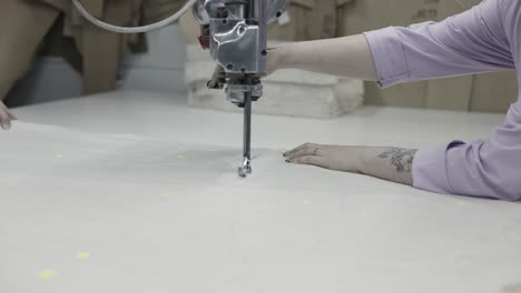 mujer que opera una máquina de corte de telas industriales