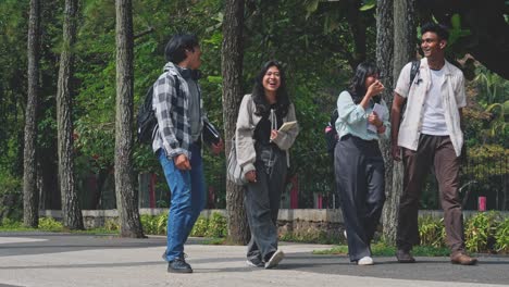 group of happy asian college students with backpacks walking and laughing together at campus park