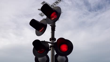 luces intermitentes de señales de cruce de vías férreas y puertas de barricadas bajo un cielo azul nublado cerca de 4k