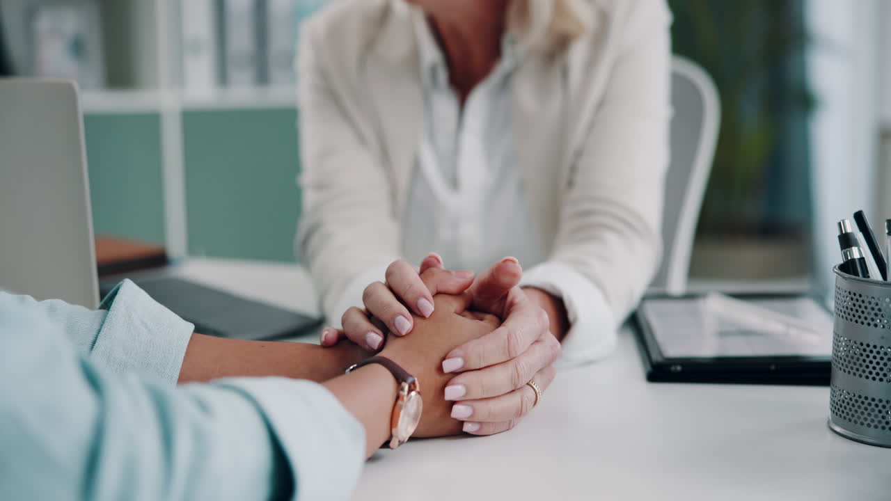 una mujer consolando a otra mujer sosteniendo sus manos.