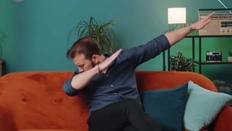 Trendy-cheerful-positive-lebanese-man-dancing-and-moving-to-rhythm-making-dub-dance-gesture-at-home